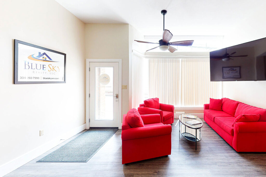 The Blue Sky Realty office lobby with two couches, a table and large flat screen TV